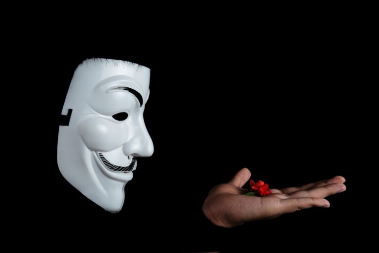 anonymous face mask looks at flower in hand